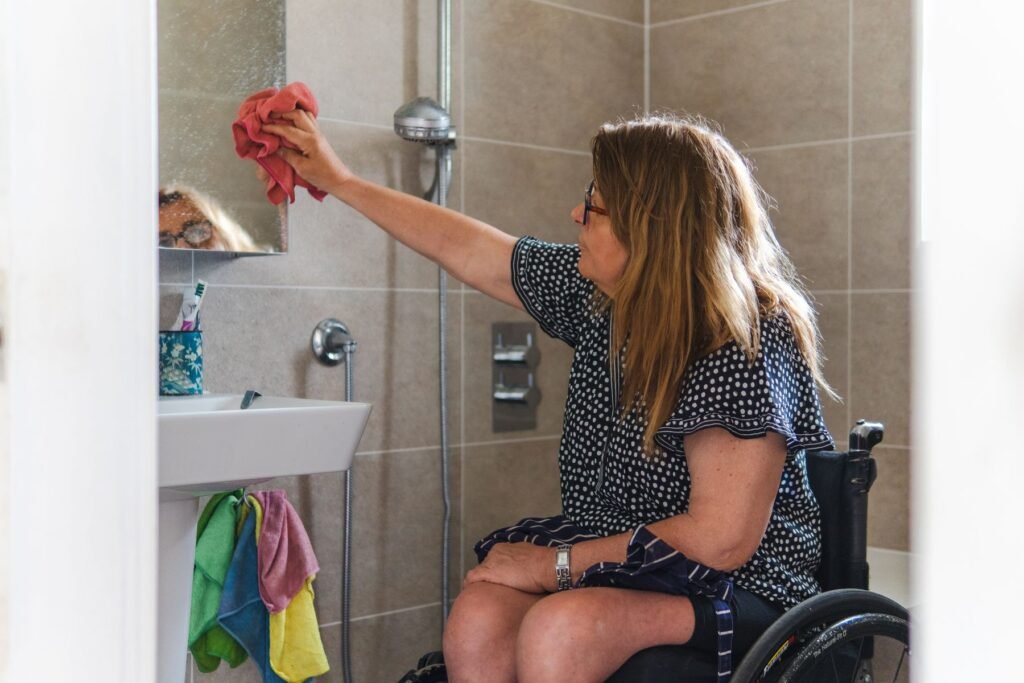 FAQ : femme en fauteuil roulant devant le miroir de sa salle de bain